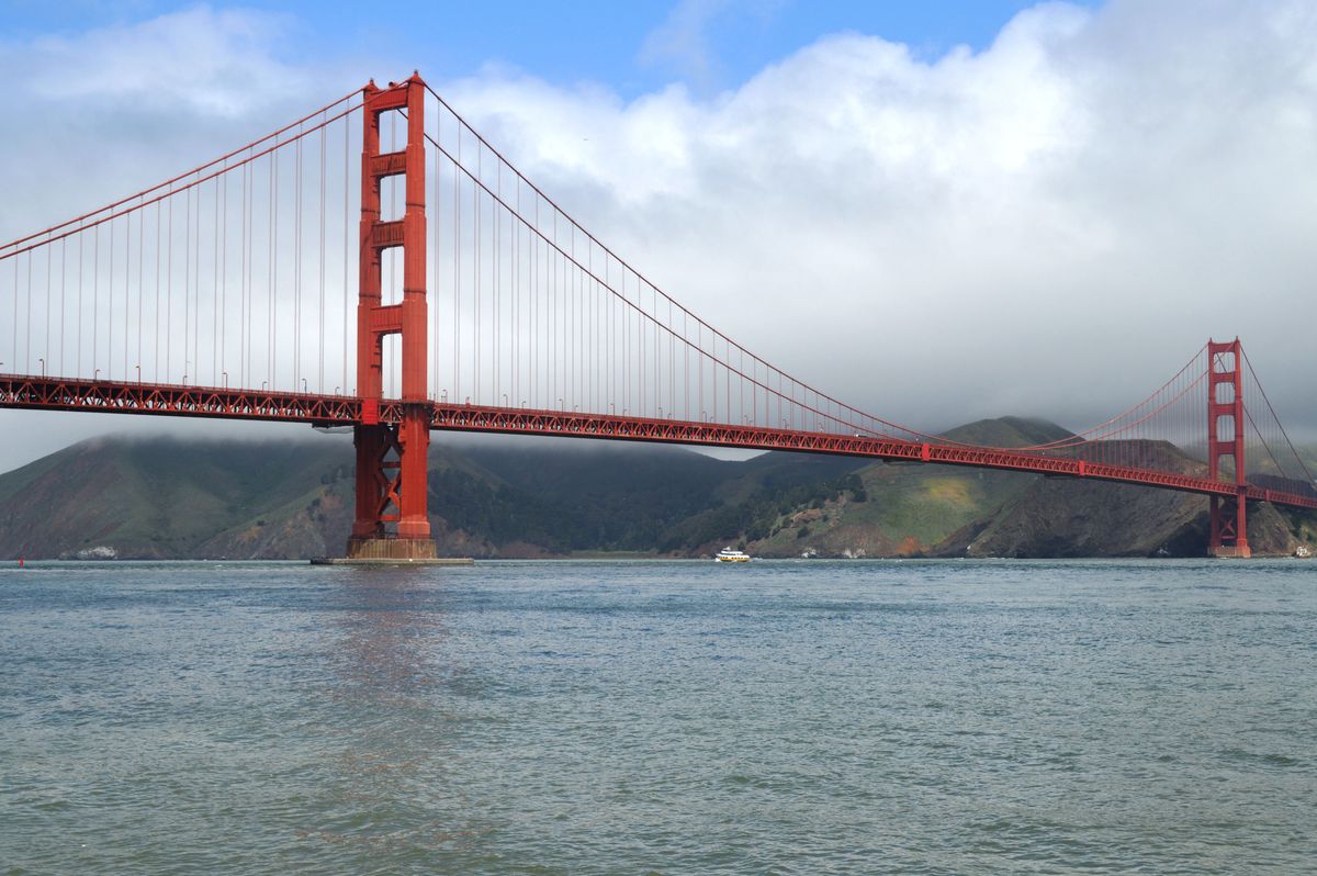 The red towers and span of the Golden Gate Bridge above San Francisco Bay, with fog over the Marin hills