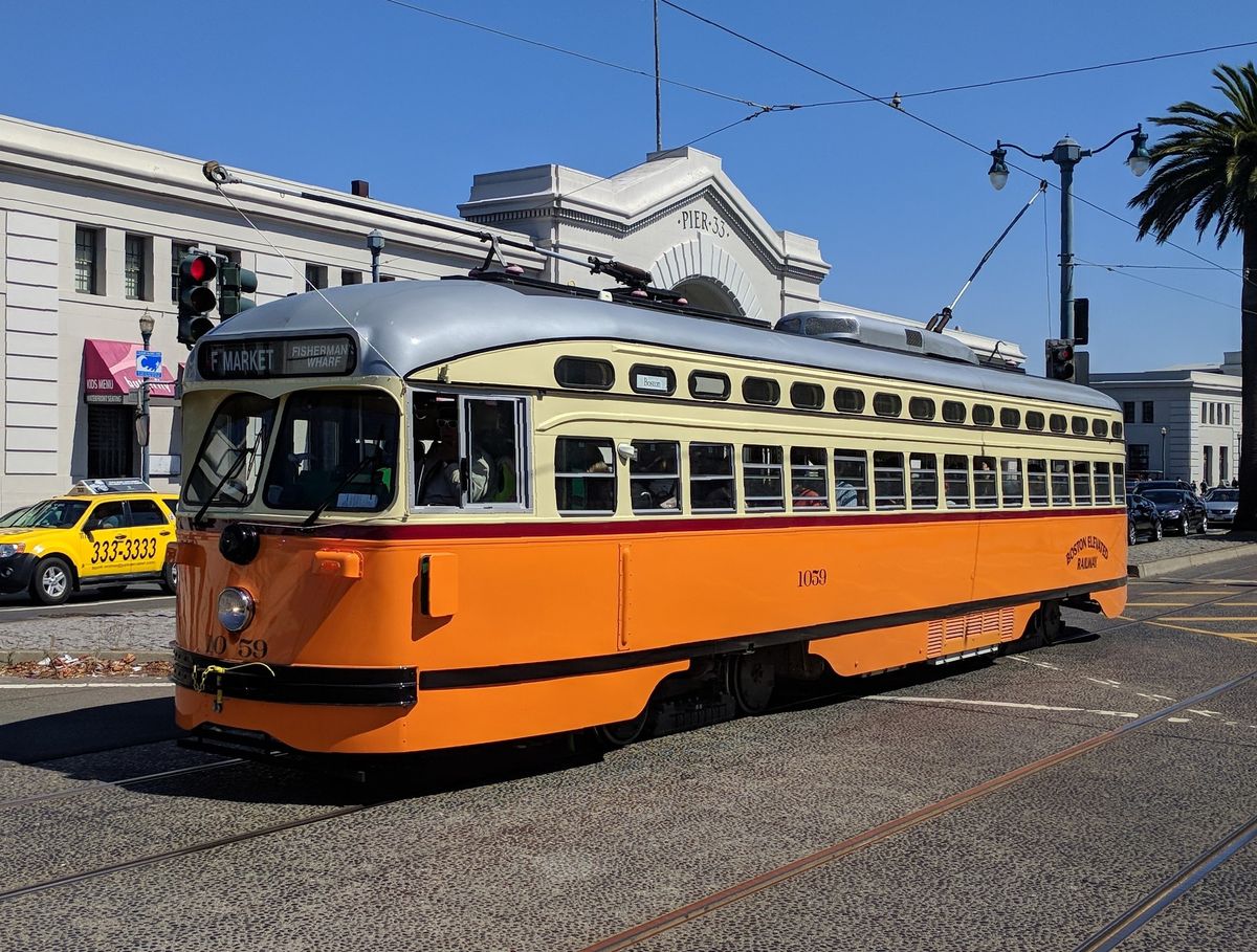Orange and cream Muni F-line historic streetcar 1059 passing Pier 33 on the Embarcadero in San Francisco